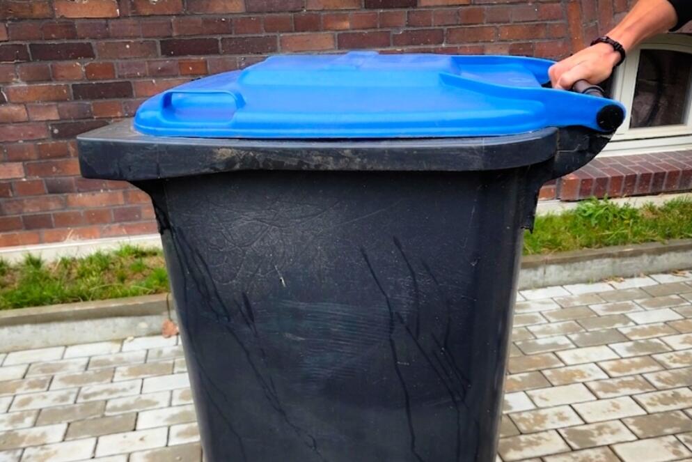 Mülltonne wird am Abholtag vom Stellplatz zur Straße geschoben